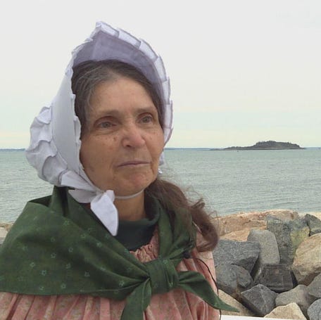 Sally Snowman, America's last lighthouse keeper, sits on rocks in front of Boston Light.