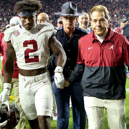 Alabama defensive back Caleb Downs and coach Nick Saban grasp hands as they walk off the field after beating Auburn in November.