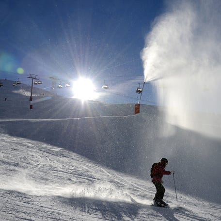 A skier descends a slope in front of a snow cannon, in Val d'Isere, French Alps, in 2012. Snowmaking can help ski areas ease the threat of climate change, but only up to a point, experts say. "It is not a climate solution," the ski industry says.