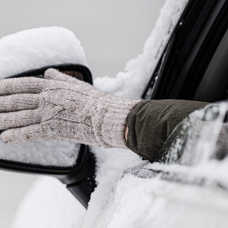 Ann Murphy cleans the snow from the rear-view mirror of her car following overnight snow, Tuesday, Jan 16, 2024, in Nether Providence Township, Pa.(Jose F. Moreno/The Philadelphia Inquirer via AP) ORG XMIT: paphq205