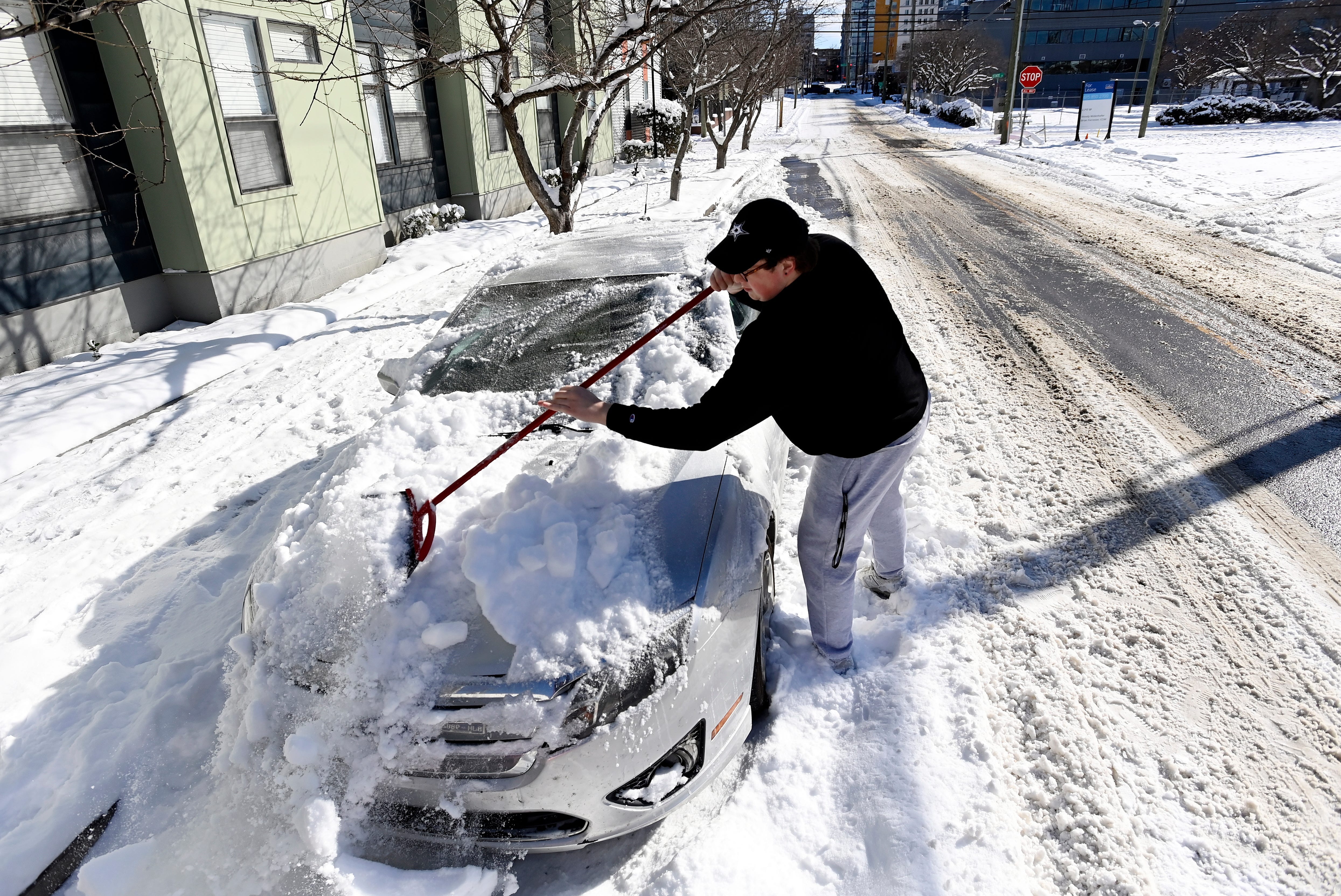 Vanderbilt University student Warner Myntti brushes snow off his car along 18th Avenue on Jan. 16, 2024, in Nashville.