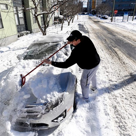 Vanderbilt University student Warner Myntti brushes snow off his car along 18th Avenue on Jan. 16, 2024, in Nashville.