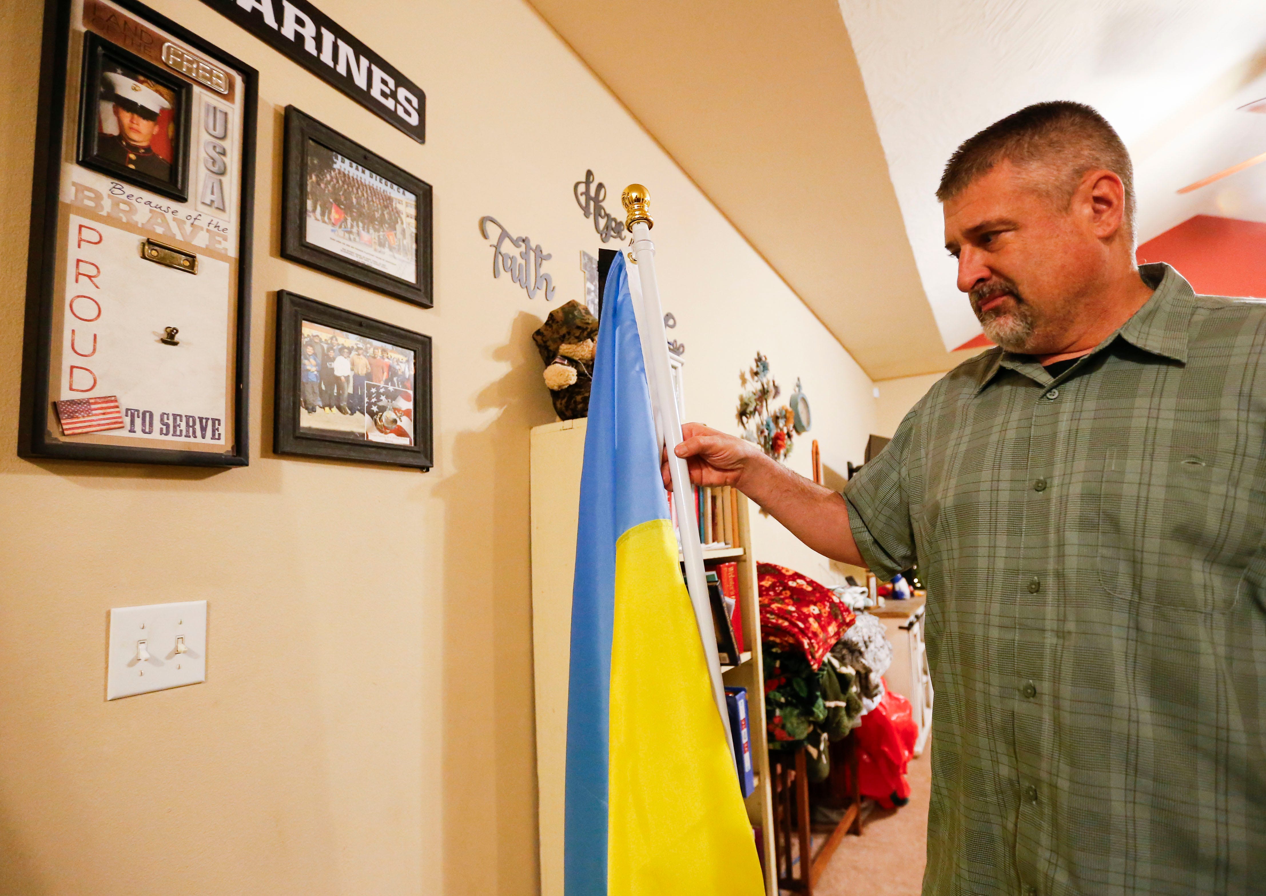 John Hertweck shows a Ukrainian flag they were sent after his son Ethan was killed while fighting for Ukraine in the embattled Donetsk region.