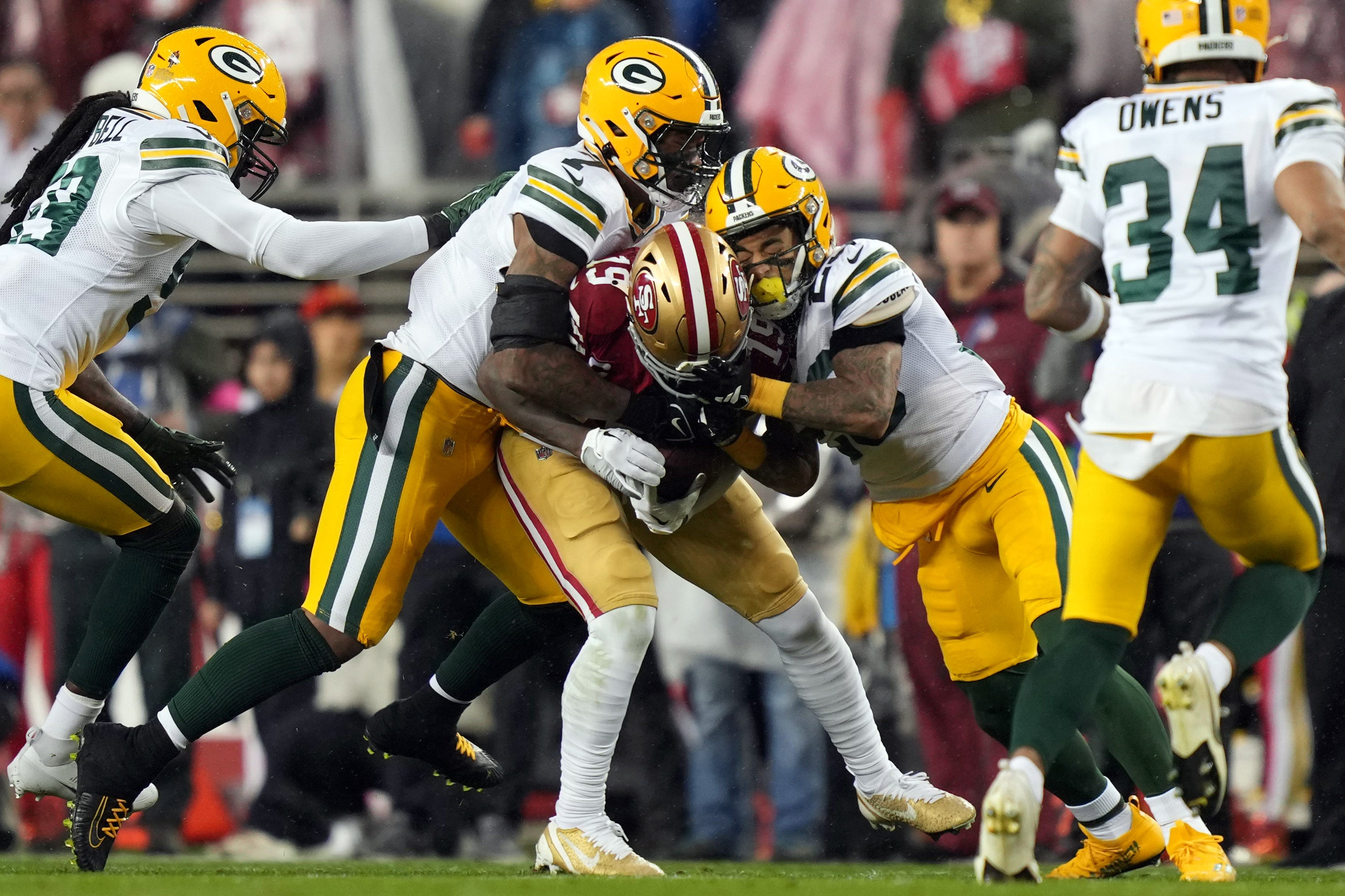 Green Bay Packers linebacker De'Vondre Campbell (59) and linebacker Quay Walker (7) and cornerback Jaire Alexander (23) tackle San Francisco 49ers wide receiver Deebo Samuel.