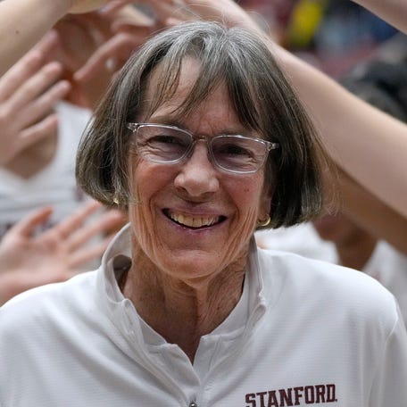 Stanford coach Tara VanDerveer smiles as players celebrate her 1,202nd victory as a college coach, tying former Duke men's basketball coach Mike Krzyzewski for the most wins.