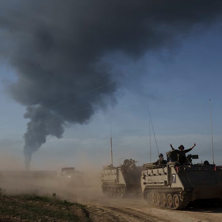Israeli soldiers move on armored personnel carriers near the Israeli-Gaza border as smoke rises to the sky in the Gaza Strip, seen from southern Israel, Sunday, Jan. 21, 2024.