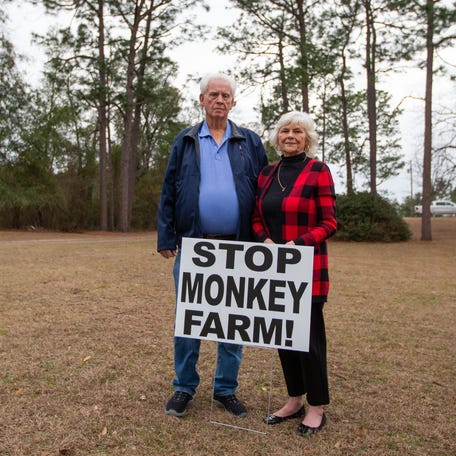 Johnny and Penny Reynolds stand in their front yard with a sign that reads "stop monkey farm!," which is to be built about 300 feet from their property in Bainbridge, Georgia, Tuesday, Jan. 23, 2024.