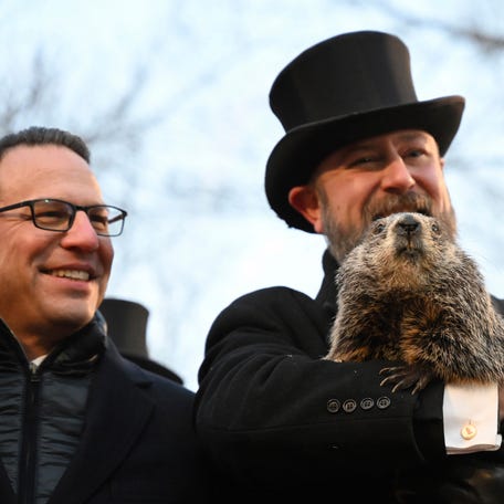 Pennsylvania Gov. Josh Shapiro looks on as A.J. Dereume holds Punxsutawney Phil last February before the groundhog predicted six more weeks of winter. PETA is hoping to replace the 137-year-old tradition with a giant gold coin flip.