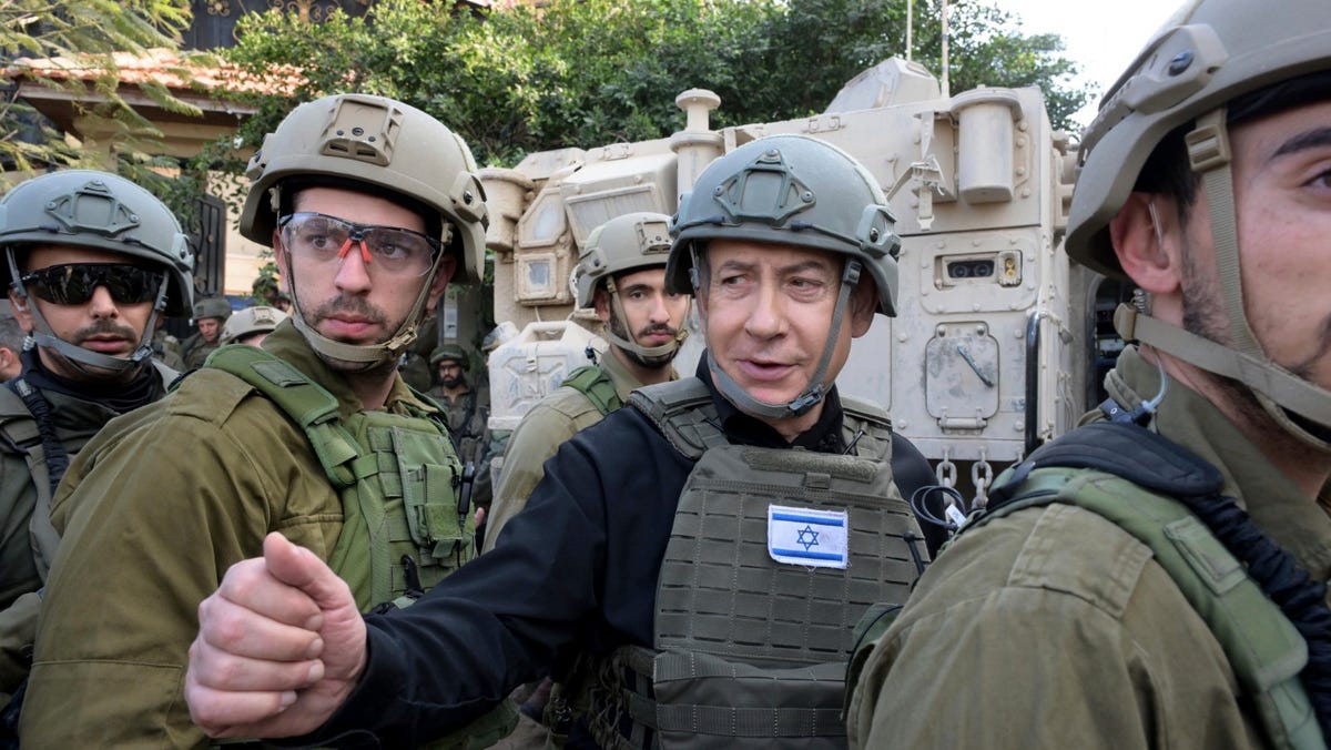 Israeli Prime Minister Benjamin Netanyahu, center, wears a protective vest and helmet as he receives a security briefing with commanders and soldiers in the northern Gaza Strip, on Monday, Dec. 25, 2023.