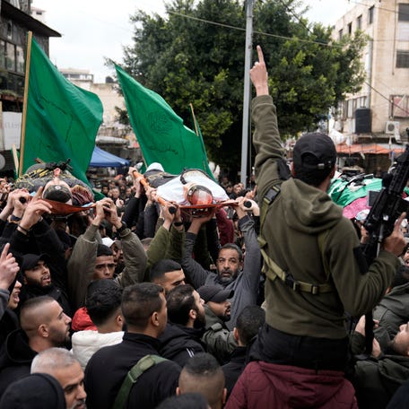 Palestinian gunmen march with bodies of militants draped in the flags of Palestinian Islamic Jihad, killed in an Israeli military raid at Ibn Sina Hospital in the West Bank town of Jenin, Tuesday, Jan. 30, 2024.