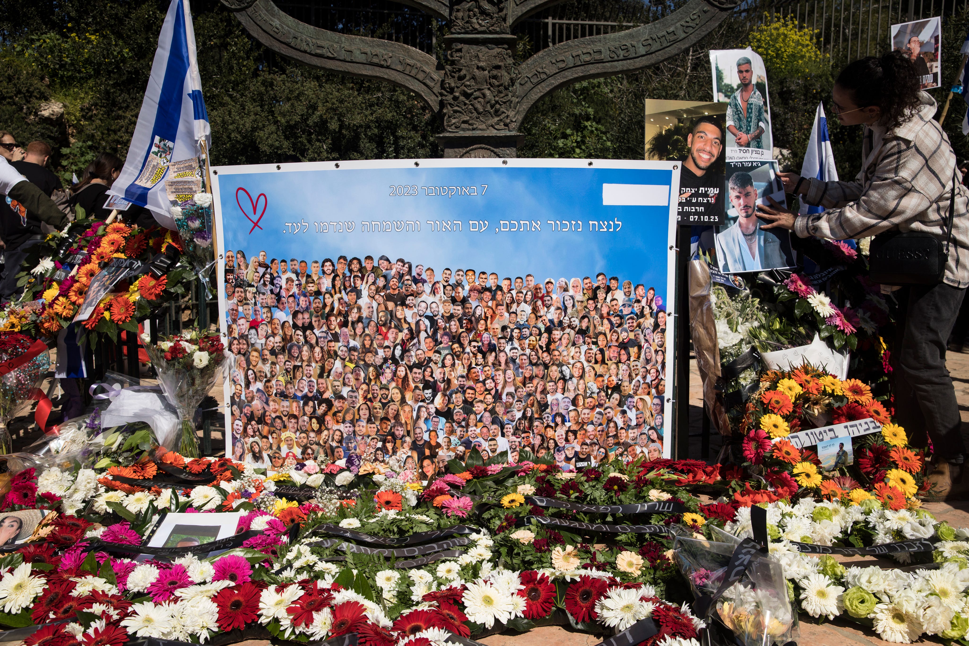 A woman hangs a photo of a man, killed during the Oct. 7 deadly Hamas attack, during a memorial event in Jerusalem on February 7, 2024. The event marked four months since the war began.