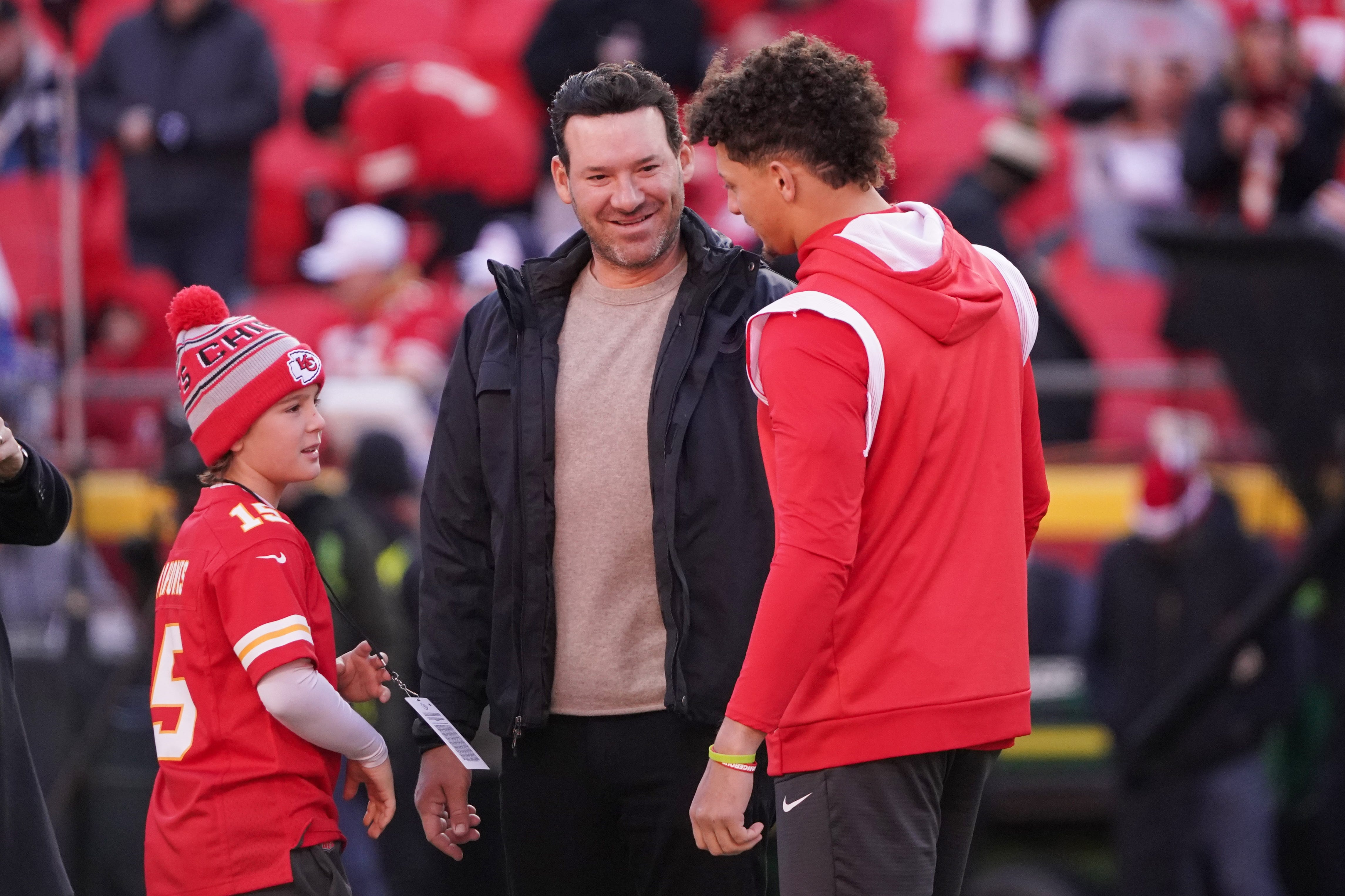 Kansas City Chiefs quarterback Patrick Mahomes (15) talks with former NFL quarterback and CBS broadcaster Tony Romo and Romo's son Rivers prior to a game against the Buffalo Bills at Arrowhead Stadium.