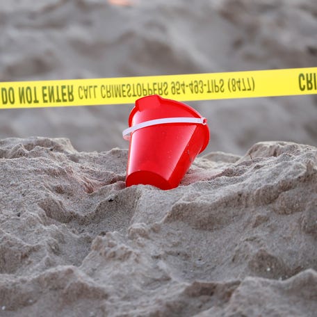 A pail rests next to caution tape on a beach in Lauderdale-by-the-Sea, Fla., on Tuesday, Feb. 20, 2024. A young girl was buried in sand and died Tuesday when a deep hole she was digging with a little boy collapsed on them both at a south Florida beach, authorities said.