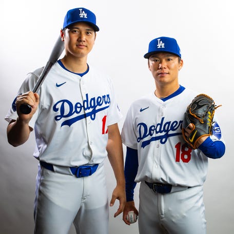 Los Angeles Dodgers designated hitter Shohei Ohtani (left) and pitcher Yoshinobu Yamamoto pose for a portrait during media day at Camelback Ranch. Both player's jerseys can be seen tucked into their pants.
