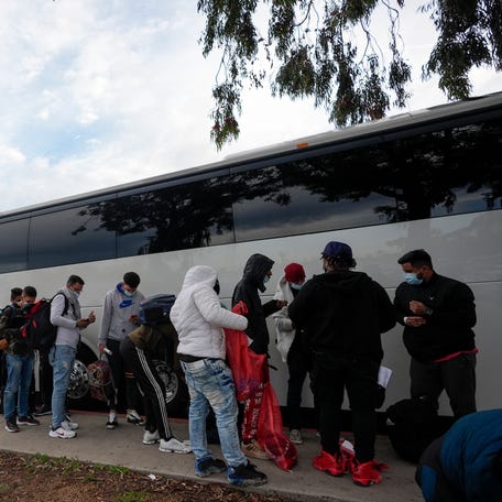 Migrants unload their items off a bus as they arrive at a bus stop after leaving a processing facility, Friday, Feb. 23, 2024, in San Diego. Hundreds of migrants were dropped off at a sidewalk bus stop after local government funding for a reception center ran out of money sooner than expected.