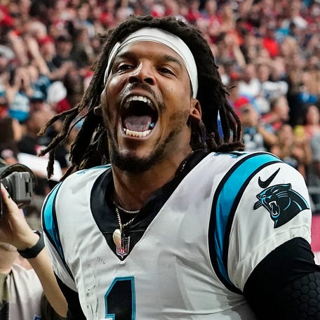 Carolina Panthers quarterback Cam Newton yells "I'm back!" after scoring a rushing touchdown against the Arizona Cardinals in a game in 2021.