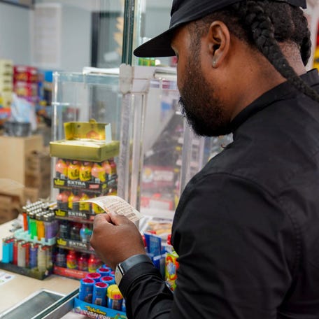 Malik Johnson, 36, of Detroit looks at the potential winning numbers of his purchased Mega Millions lottery ticket on Tuesday, Aug. 8, 2023. Some states allow lottery winners to collect anonymously,
