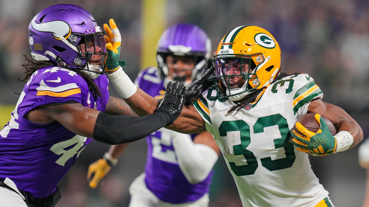 Dec 31, 2023; Minneapolis, Minnesota, USA; Green Bay Packers running back Aaron Jones (33) runs with the ball against the Minnesota Vikings safety Josh Metellus (44) in the first quarter at U.S. Bank Stadium. Mandatory Credit: Brad Rempel-USA TODAY Sports