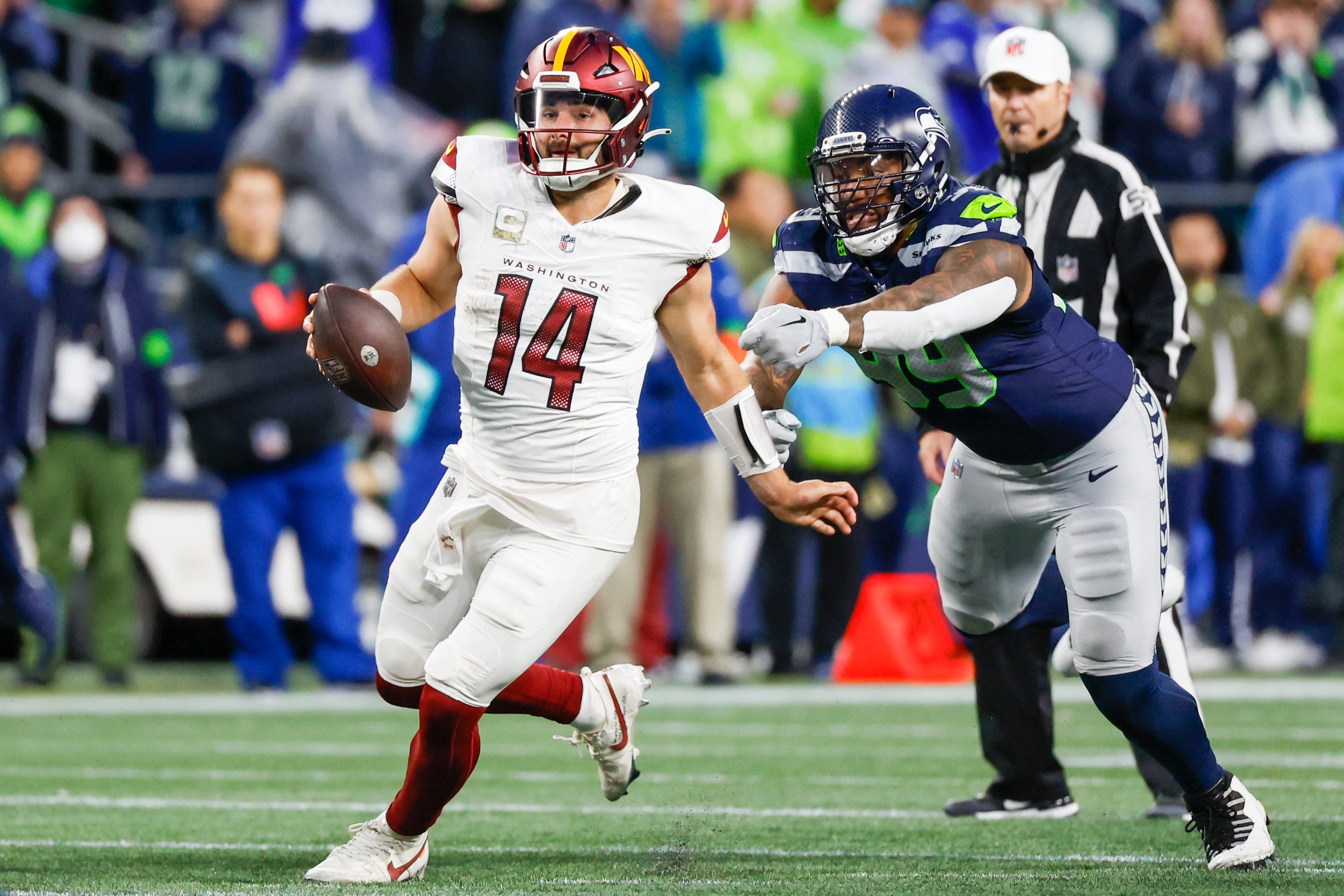 Nov 12, 2023; Seattle, Washington, USA; Washington Commanders quarterback Sam Howell (14) escapes a sack by Seattle Seahawks defensive end Leonard Williams (99) during the fourth quarter at Lumen Field. Mandatory Credit: Joe Nicholson-USA TODAY Sports