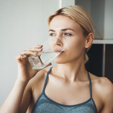 Woman drinking water at home in kitchen