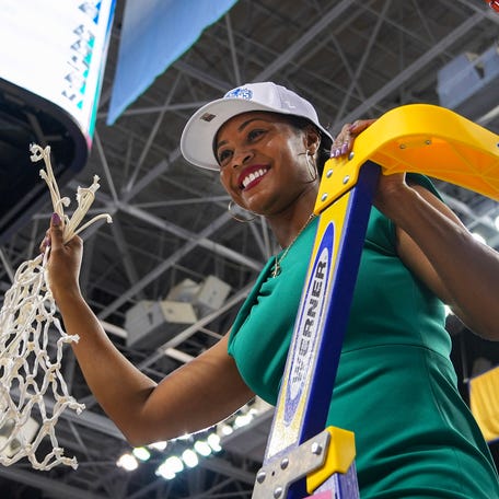 Notre Dame Fighting Irish head coach Niele Ivey displays the tournament net after defeating the NC State Wolfpack at Greensboro Coliseum.