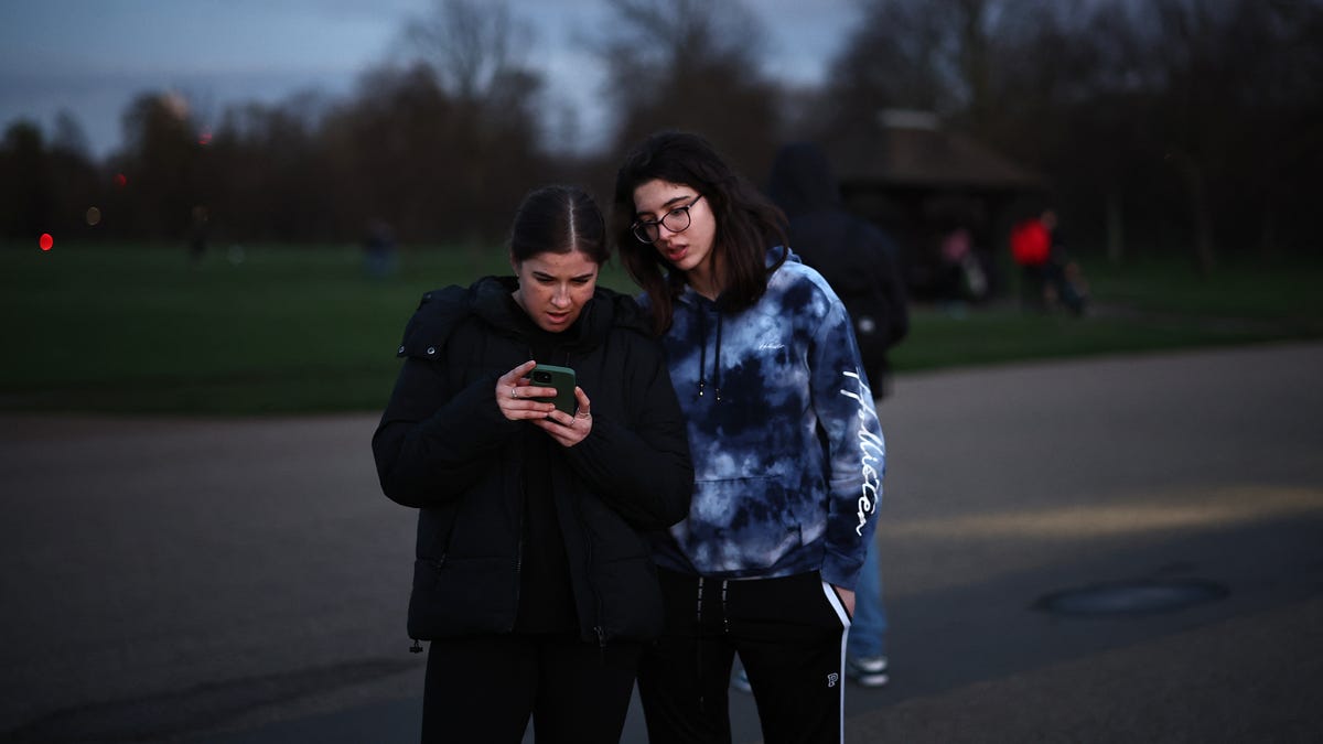 People watch a recording by Britain's Catherine, Princess of Wales, outside Kensington Palace in London on March 22, 2024. Britain's Catherine, Princess of Wales, announced that she has cancer and was in the early stages of chemotherapy, asking for "time, space and privacy" as she finishes her treatment.