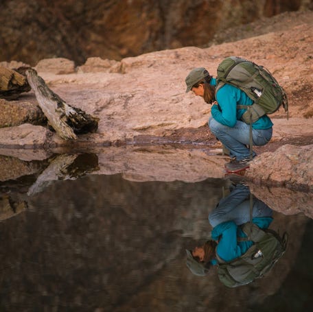 A visitor is reflected in Bear Gulch Reservoir in Pinnacles National Park.
