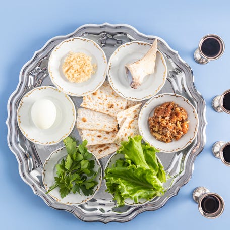 A pesach plate with traditional symbols of the Jewish Passover and four glasses of red kosher wine.
