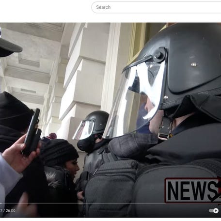 Video shot by a freelance journalist shows the woman in the black beanie crowding past a police officer and into the Capitol on Jan. 6, 2021.