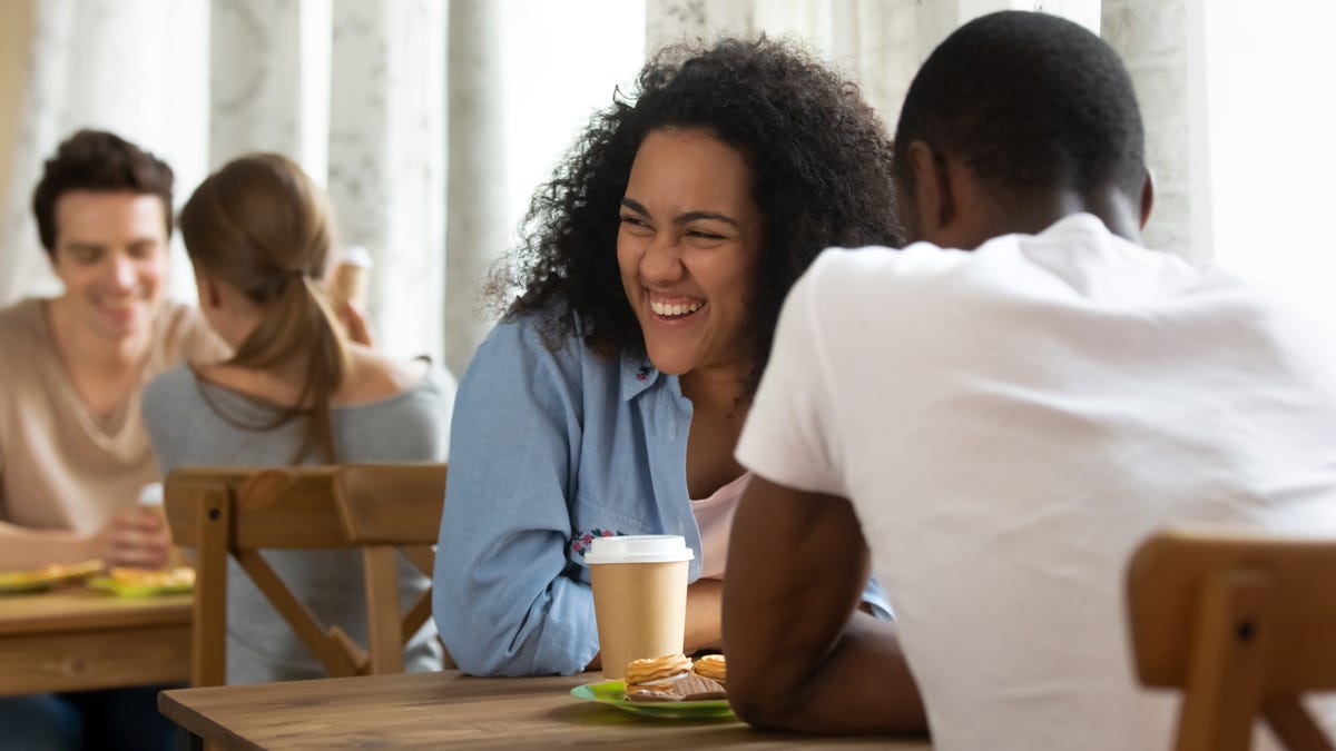 Happy young mixed race girl attending speed dating, getting acquainted with interesting people, joking, laughing, having fun. Millennial woman meeting black friend, enjoying spending time together.