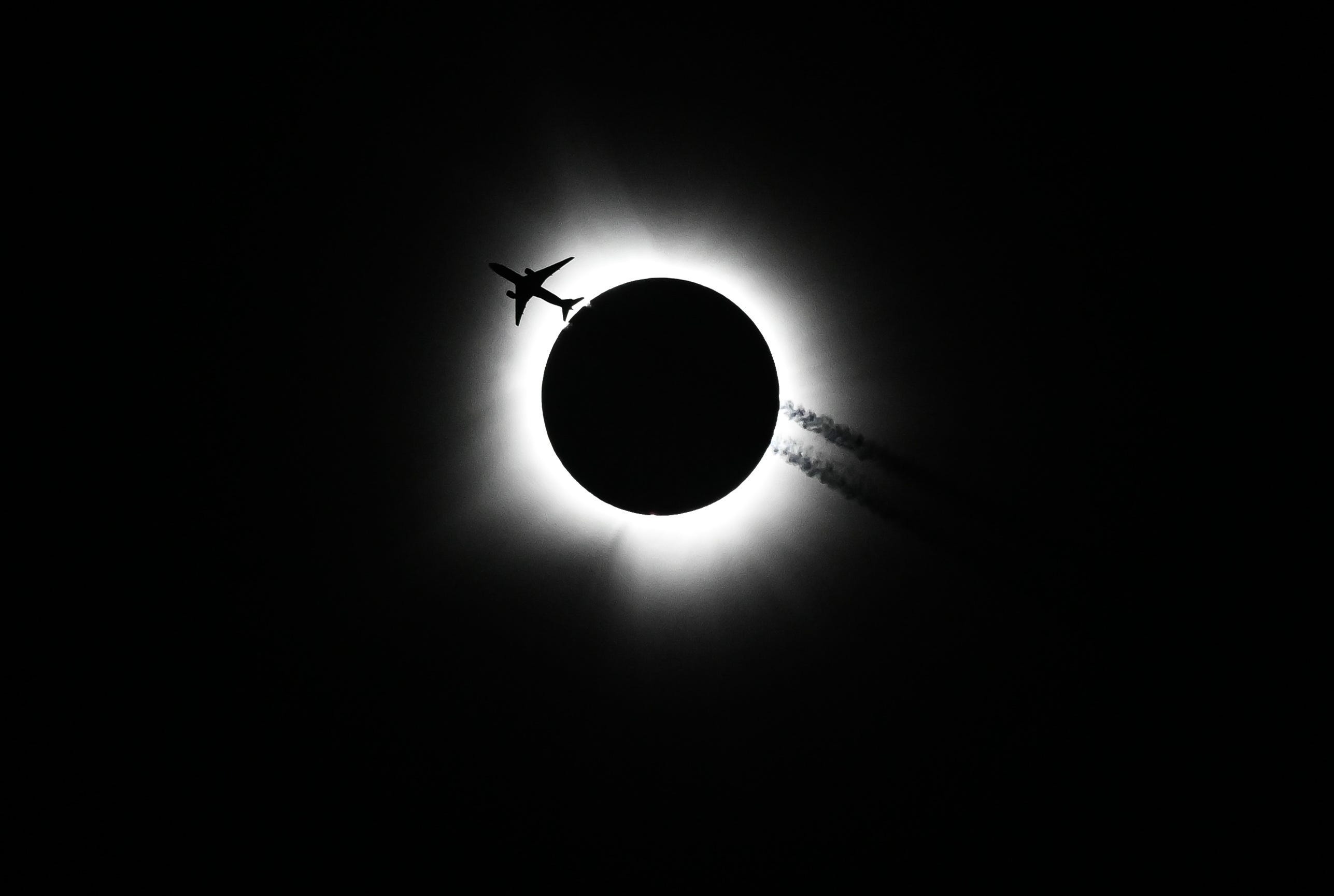 April 8, 2024: An airplane passes near the eclipse during the Hoosier Cosmic Celebration at Memorial Stadium on Monday, April 8, 2024.