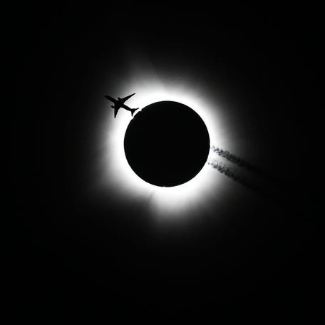 April 8, 2024: An airplane passes near the eclipse during the Hoosier Cosmic Celebration at Memorial Stadium on Monday, April 8, 2024.