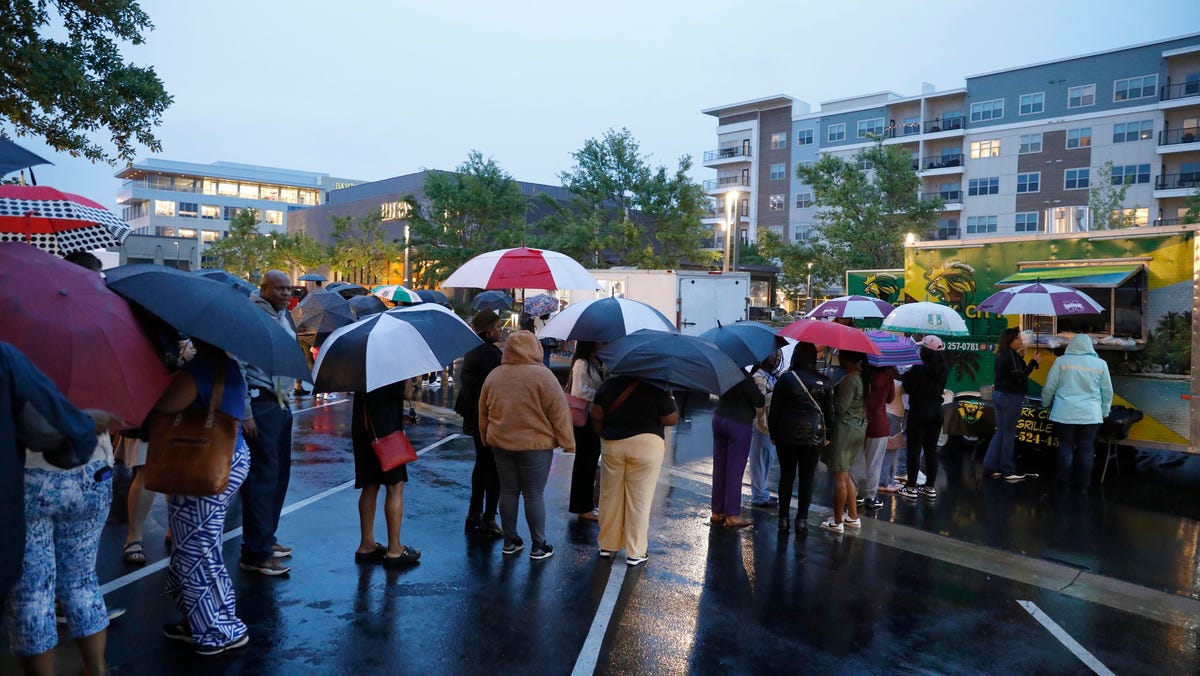 Attendees of the Taste of Mississippi event wait in line in the rain in Jackson, Miss., on April 8, 2024.