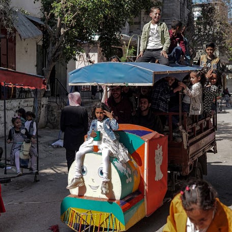 Children ride atop a motorcycle cart converted into a makeshift trackless train vehicle as they celebrate the Muslim holiday of Eid al-Fitr, after the end of the holy month of Ramadan, in Deir el-Balah in the central Gaza Strip on April 10, 2024.