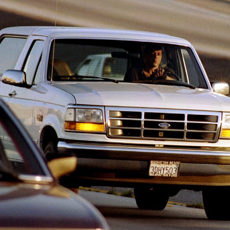 A Ford Bronco carrying OJ Simpson (hidden in the rear seat) is reportedly driven by Simpson's former teammate Al Cowlings, chased by dozens of police cars during an hours-long pursuit through Los Angeles area freeways, June 17, 1994.