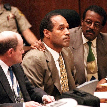 Lead defense attorney Johnnie Cochran (R) puts his arm on O.J. Simpson's (C) shoulder after Simpson told Judge Lance Ito 22 September 1995 in Los Angeles, CA, that he has faith that jurors will acquit him of the murder of his ex-wife Nicole Simpson and her friend, Ronald Goldman. At left is defense attorney Robert Blasier (L). AFP PHOTO/POOL (Photo by REED SAXON / POOL / AFP) (Photo by REED SAXON-/POOL/AFP via Getty Images)