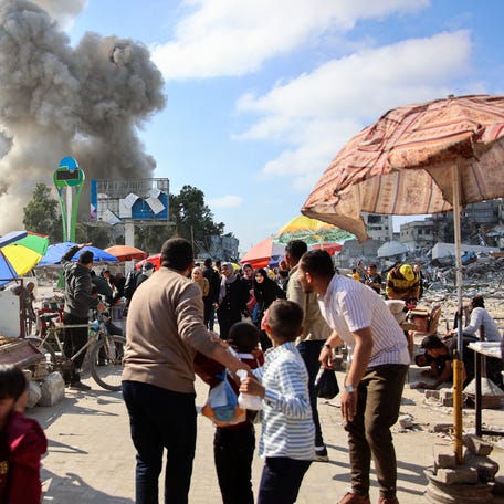 Palestinians look at smoke billowing during Israeli bombardment on the Firas market area in Gaza City on April 11, 2024.