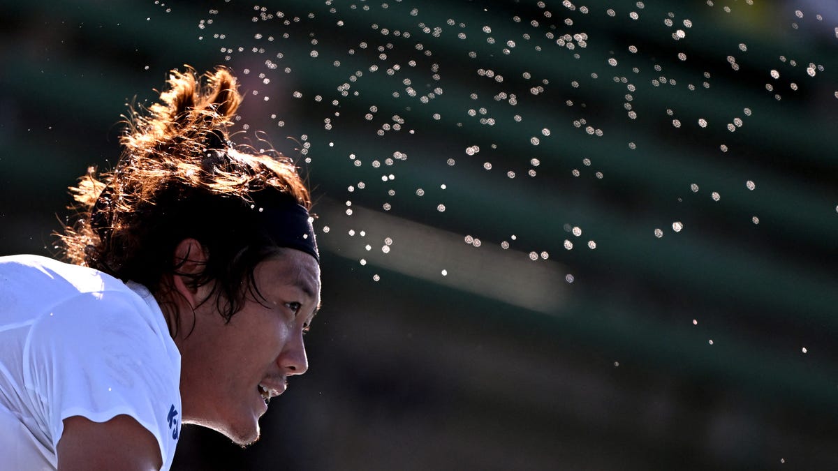 Sweat sprays from Zhang Zhizhen of China during his men's singles match against Frances Tiafoe of the US at the Kooyong Classic tennis tournament in Melbourne on January 10, 2024.