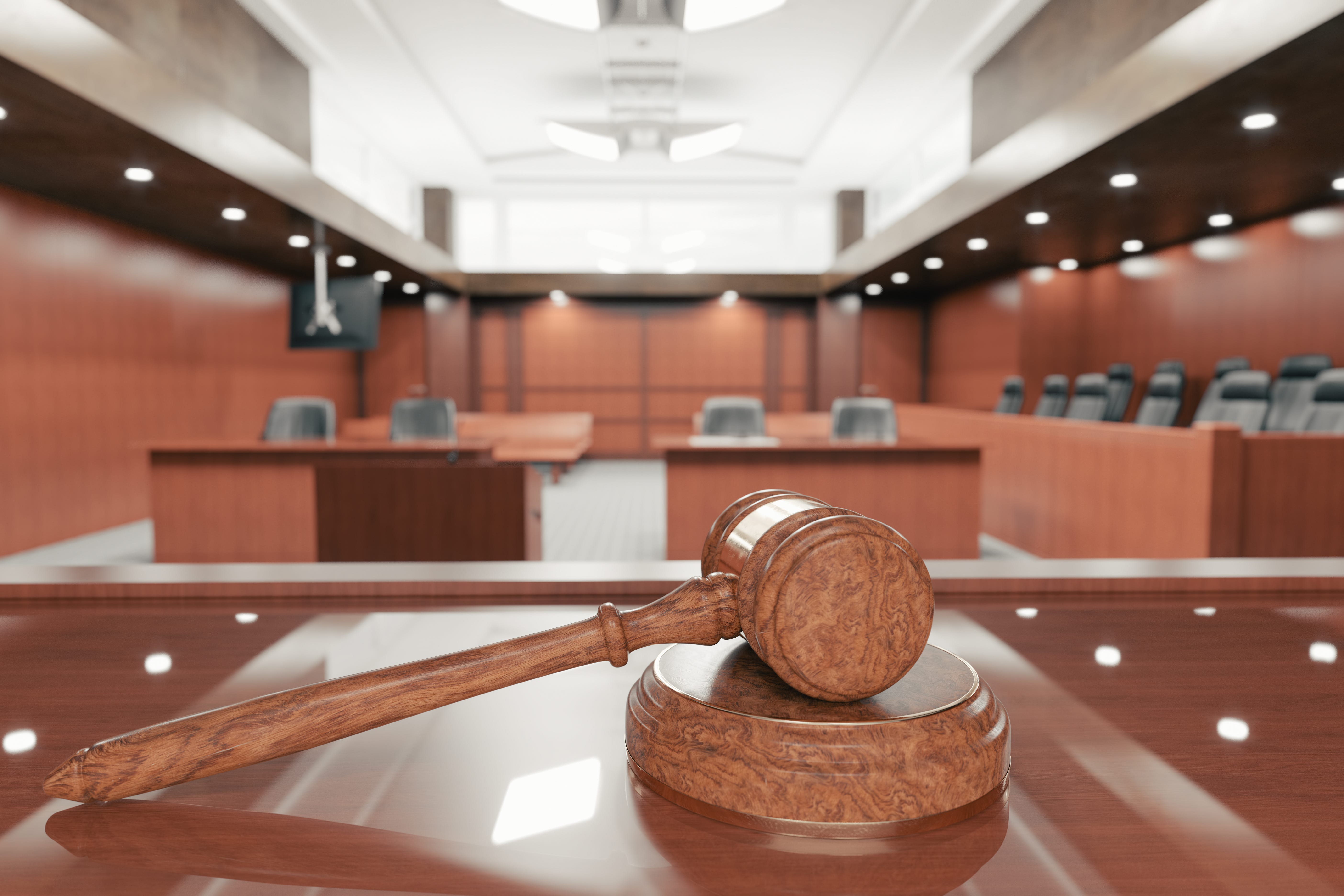 Pictured is the interior of an empty courtroom with gavel and sounding block on the desk.