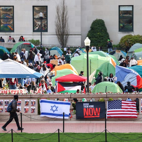 A man walks past Israeli and US flags alongside portraits of Israelis taken hostage by the militant Palestinian group Hamas in front of the pro-Palestinian encampment at Columbia University in New York on April 23, 2024.