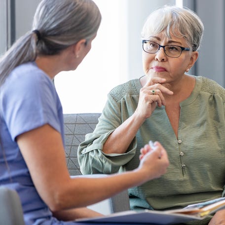 A senior adult woman listening carefully as a female doctor explains a diagnosis to her.