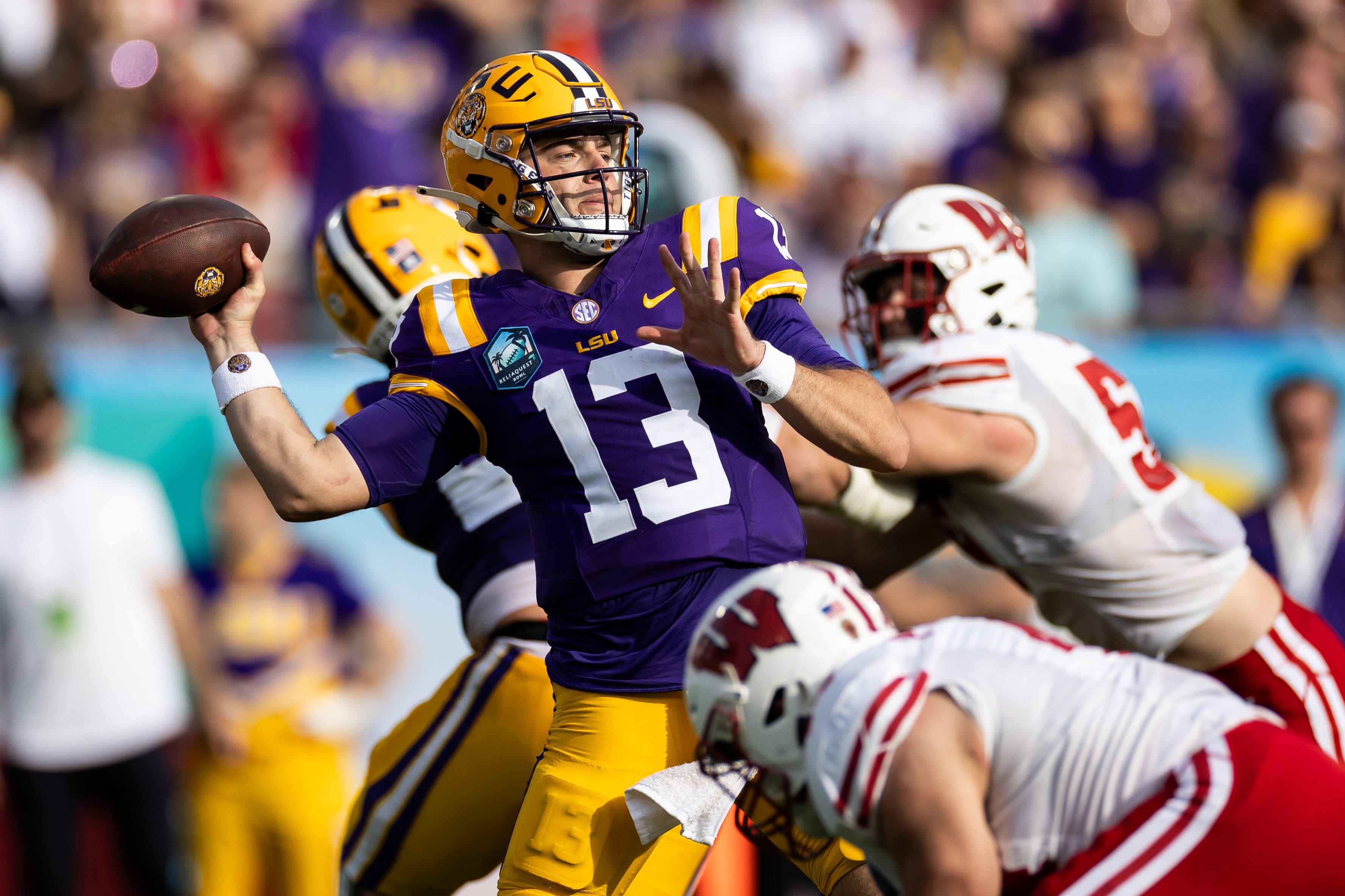 LSU quarterback Garrett Nussmeier (13) throws the ball under pressure against Wisconsin during the 2024 Reliaquest Bowl at Raymond James Stadium.