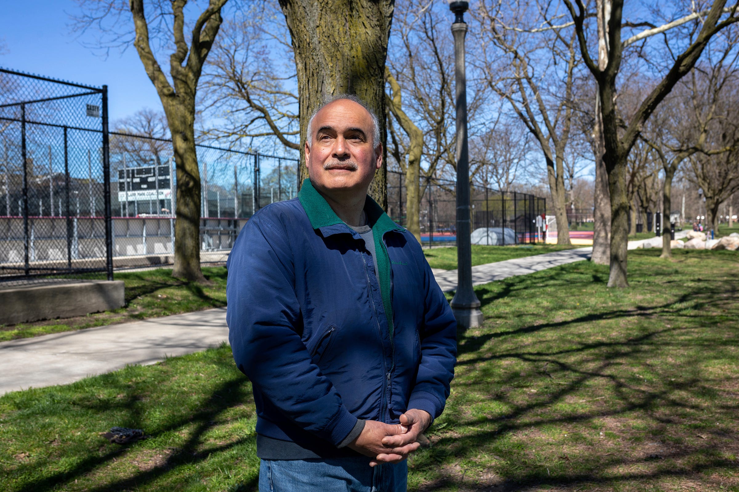 Anthony Benavides, director of the Clark Park Coalition, a nonprofit organization providing recreational, educational, and social skills programming, stands in front of a tree at Clark Park in southwest Detroit on Saturday, April 13, 2024.