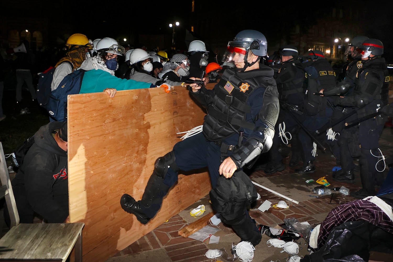 A California Highway Patrol officers kicks a wooden piece of ply-wood that was used to construct the barricade on the eastern wall of the Gaza Solidarity Encampment. Pro-Palestinian protesters clash with law enforcement as officials clear demonstrator encampments on UCLA's campus on May 2, 2024 in Los Angeles.