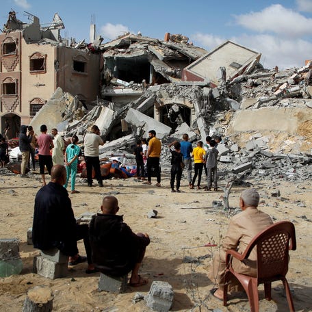 Palestinians look at the site of an Israeli strike on a house in in Rafah amid the ongoing conflict between Israel and Hamas.