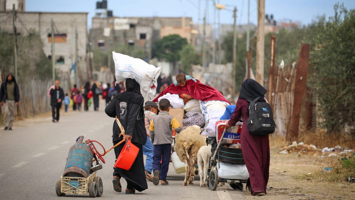 Displaced Palestinians in Rafah in the southern Gaza Strip carry their belongings as they leave following an evacuation order by the Israeli army on May 6, 2024.