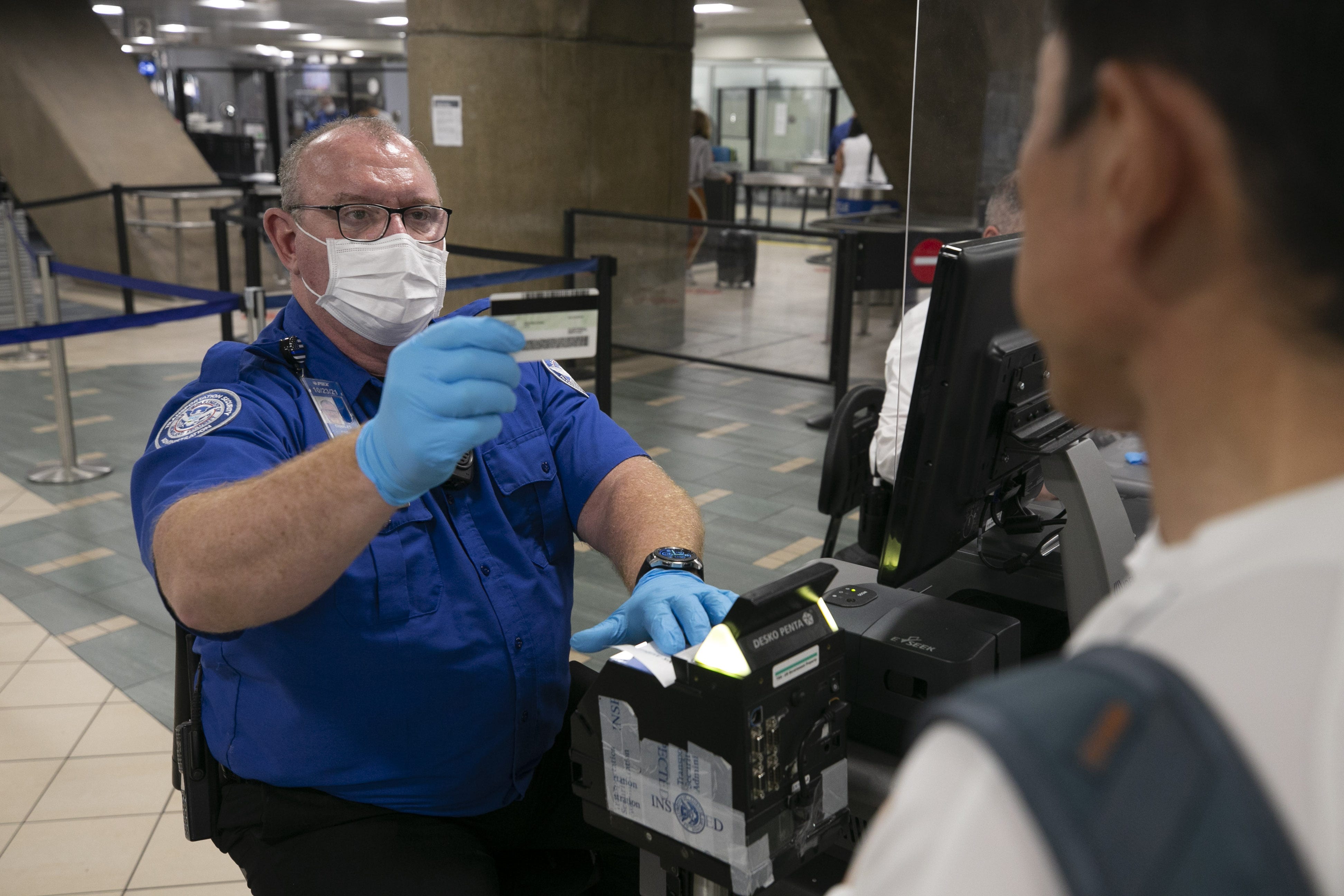 Chuck Griep, a TSA officer, checks the identification of a traveler at security in Terminal Four at Phoenix Sky Harbor International Airport on June 3, 2021.