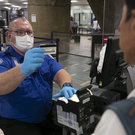 Chuck Griep, a TSA officer, checks the identification of a traveler at security in Terminal Four at Phoenix Sky Harbor International Airport on June 3, 2021.