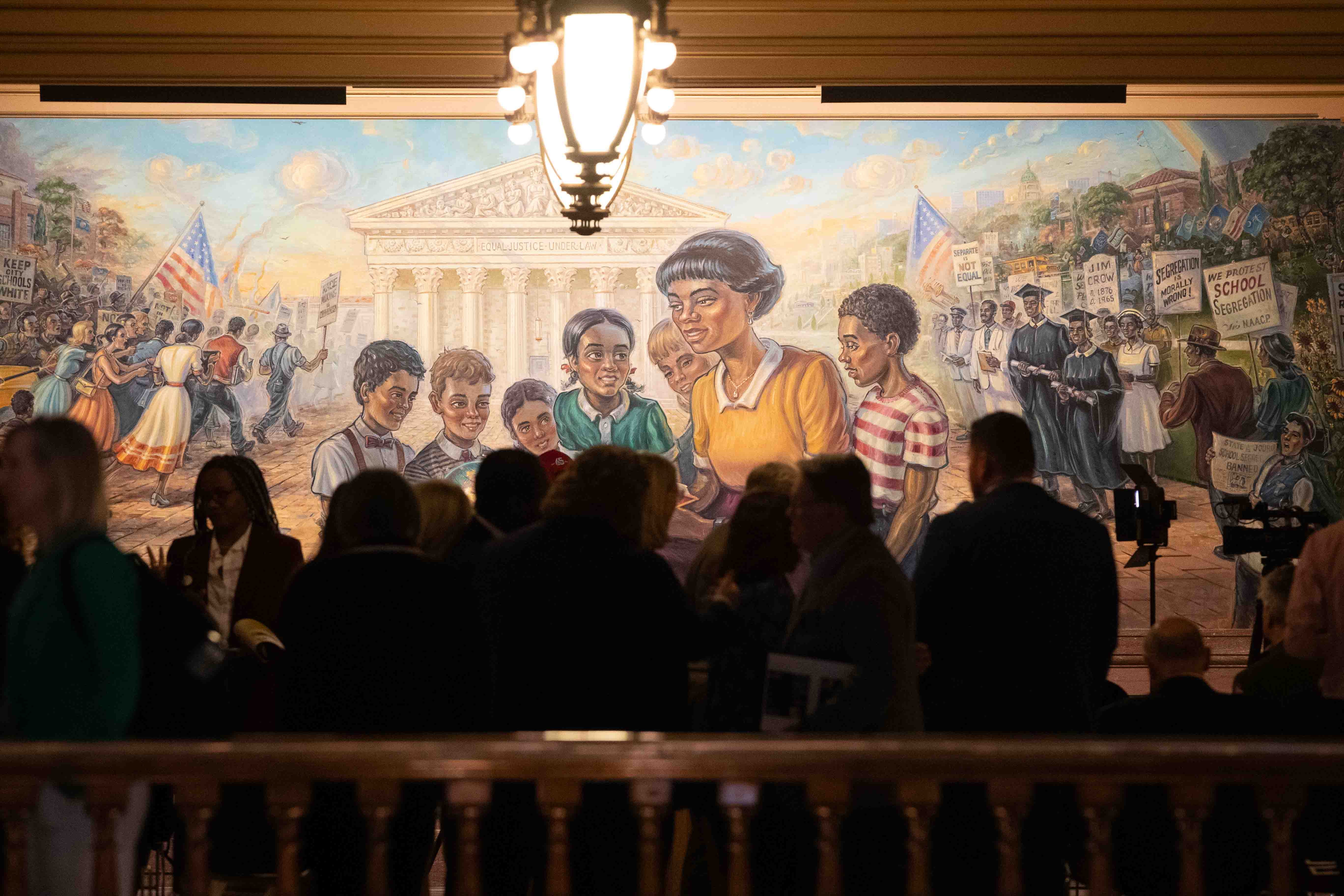 People mill around the third floor of the Kansas Statehouse in front of a Brown v. Board of Education mural before hearing from speakers recognizing the 70th anniversary of the landmark Supreme Court case Monday, April 29. (Via OlyDrop)