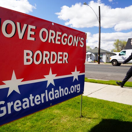 A person walks past a sign in Prineville, Oregon, urging voters to approve a measure shifting the state border so half of the state would join Idaho to the east.